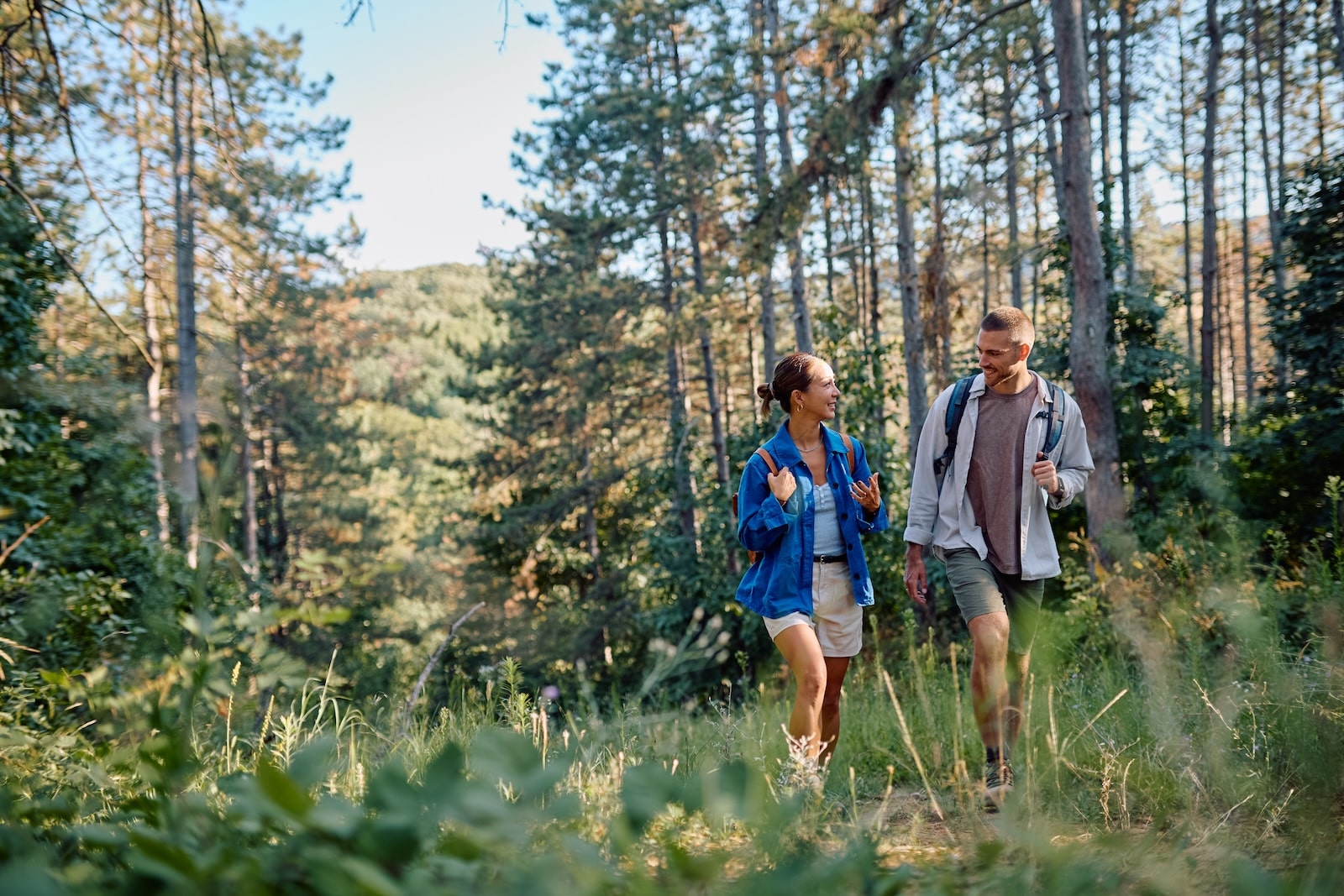 Couple of hikers with backpacks walking in a forest path and talking at the Hyde Memorial State Park.